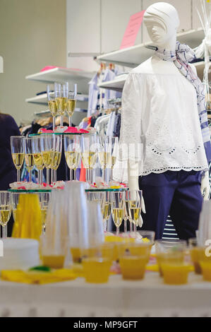 buffet table with snacks, cakes, drinks and champagne. slide champagne on the background of a clothing store and a mannequin Stock Photo