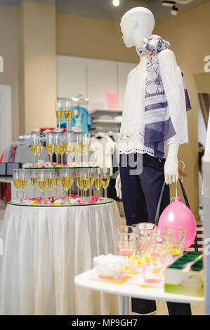 buffet table with snacks, cakes, drinks and champagne. slide champagne on the background of a clothing store and a mannequin Stock Photo