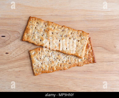 Top view of two multigrain flatbread crackers on a wood cutting board. Stock Photo