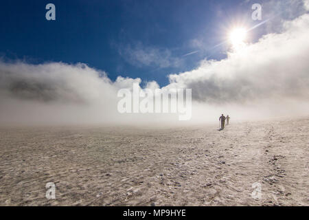 two men on snowy field in kamchatka mountains with clouds and sky above Stock Photo