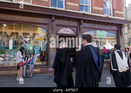 Cambridge UK-2018-May-19, Graduates in conversation on pavement with outfitters in background. Stock Photo