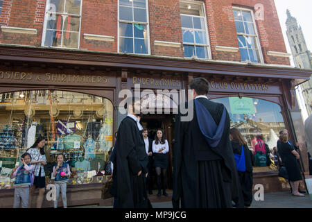 Cambridge UK-2018-May-19, Graduates in conversation on pavement with outfitters in background. Stock Photo