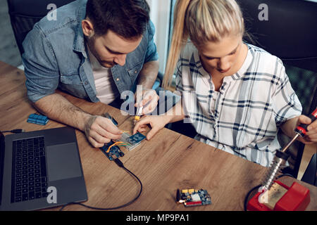 Top view on two engineers who soldering elements of circuit board. Stock Photo