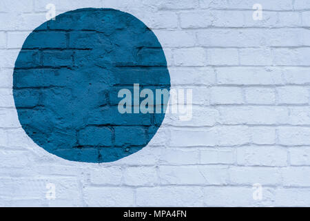 Drawn painted blue circle on a light brick wall bricks surface of wall, as graffiti. Graphic abstract modern background. Modern iconic urban culture, stylish pattern Stock Photo