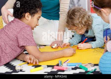 Preschool kids having fun during group painting in kindergarten Stock Photo