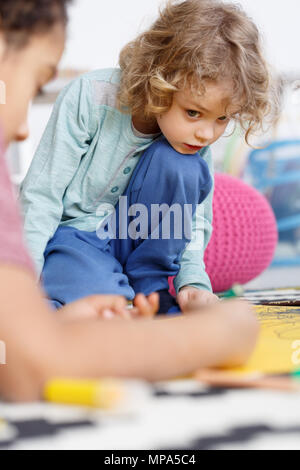 Preschool creative boy painting with friends in kindergarten Stock Photo