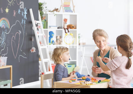 Preschool children in kindergarten sticking with plasticine on classes Stock Photo