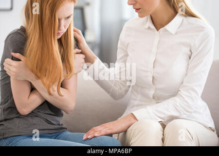 Female professional psychologist comforting upset woman on a sofa in the office Stock Photo