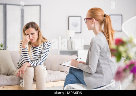 Unhappy woman suffering from depression crying during session at psychologist's office Stock Photo
