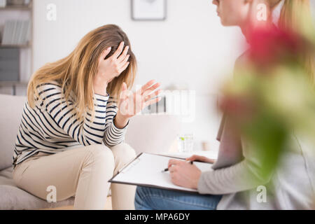 Exhausted woman at psychology clinic, having nervous breakdown feeling hopeless and frustrated Stock Photo