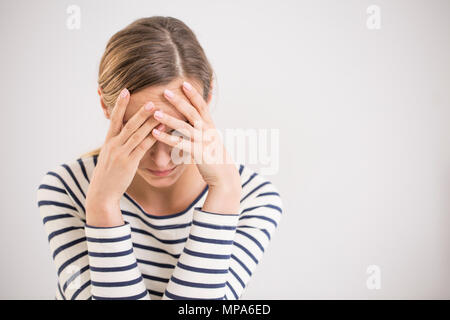 Young hopeless woman suffering from depression having nervous breakdown holding her head on isolated background, copy space Stock Photo