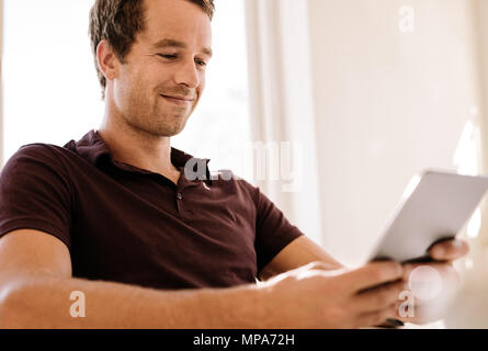Entrepreneur operating digital tablet. Close up of a smiling man working on digital tablet. Stock Photo