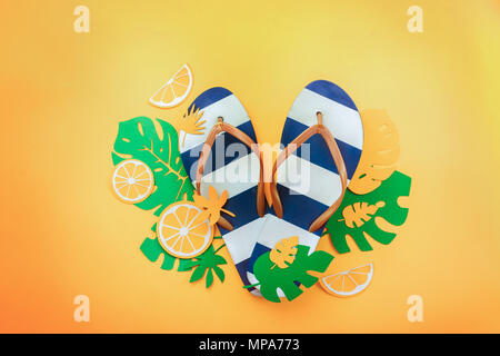 Summer vacation flat lay with tropical leaves and beach flip-flops on a sunny yellow background with copy space Stock Photo