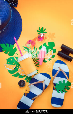 Summer travel flat lay with sunglasses, sunscreen, flip-flops, hat, binoculars and compass on a sunny yellow background with copy space Stock Photo