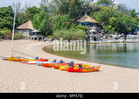 Multi-coloured kayaks for leisure and watersports on the sandy beach shore at Kaya Mawa, Likoma Island, Lake Malawi, Malawi, south-east Africa Stock Photo