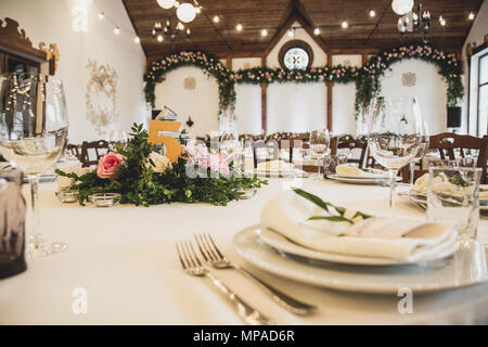 wedding table in the restaurant with a lot of transparent glasses, napkins and decoration of dishes. Stock Photo