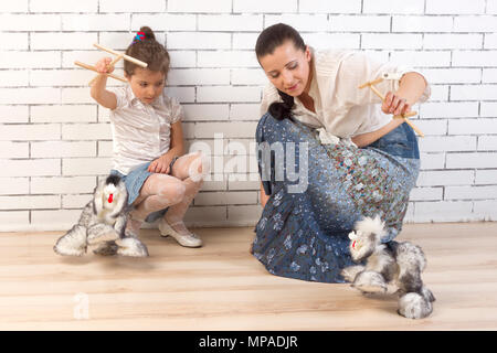 Mother and 5 year old daughter playing with a toy dog Stock Photo