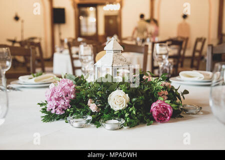 wedding table in the restaurant with a lot of transparent glasses, napkins and decoration of dishes. Stock Photo