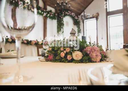 luxury wedding decor with flowers and glass vases and number of setting on round tables. arrangements of decorations at wedding reception. expensive catering. space for text Stock Photo