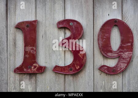 House number one three nine made of dark red ceramic on wooden wall. Stock Photo