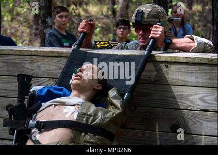 U.S. Army Capt. Timothy Cox, 3rd Chemical Brigade, Maneuver Support Center of Excellence, carries a simulated patient over an obstacle  during the Best Ranger Competition 2017 at Ft. Benning, Ga., April 8, 2017. The 34th annual David E. Grange Jr. Best Ranger Competition 2017 is a three-day event consisting of challenges to test competitor's physical, mental, and technical capabilities. Stock Photo