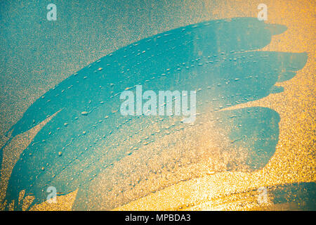 Close-up imprints of the fingers on the water dust sprayed window. Blue shades mixing with orange shades of shining sunset light. Ideal background for illustrations, collages. Artistic retouching. Stock Photo