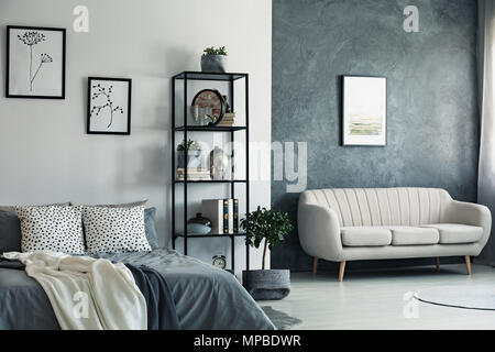 Beige sofa against concrete wall with painting in bedroom with drawings on white wall Stock Photo