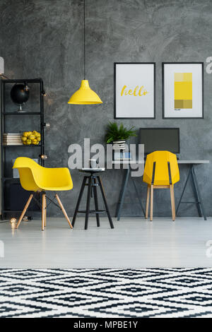 Scandinavian room with workspace, patterned rug, wall and yellow details Stock Photo