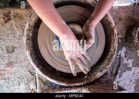 Child hands shaping bowl on potters wheel. Overhead shot Stock Photo