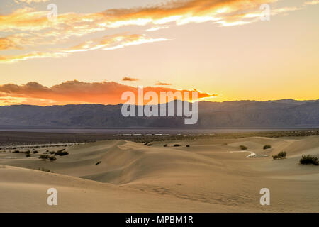 Sunset Sand Dunes - Spring sunset at Mesquite Flat Sand Dunes, with Stovepipe Wells village seen at base of Panamint Range. Death Valley National Park Stock Photo