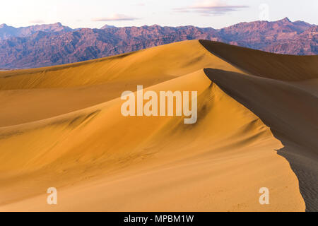 Sunset Sand Dunes - A Spring sunset view of rolling Mesquite Flat Sand Dunes standing tall at front of Amargosa Range. Death Valley National Park, USA Stock Photo
