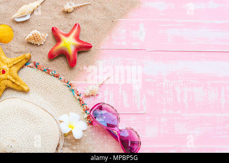Beach accessories including sunglasses, starfish, hat beach and shell on bright pink pastel wooden background for summer holiday and vacation concept. Stock Photo