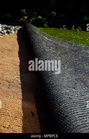 Laying artificial grass turf onto sand in a back garden yard Stock Photo