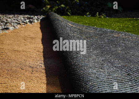 Laying artificial grass turf onto sand in a back garden yard Stock Photo