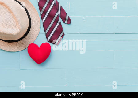 Happy fathers day concept. Red tie, man hat and handmade red heart on bright blue pastel wooden table background. Stock Photo