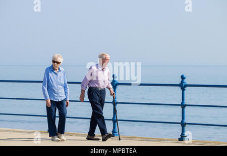 Elderly couple walking along seafron on sunny day. UK Stock Photo