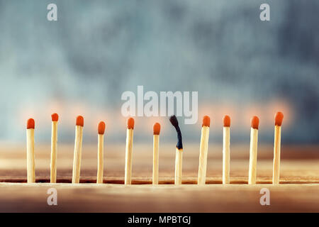 matches in a row on a wooden background. One match burned, died out Stock Photo