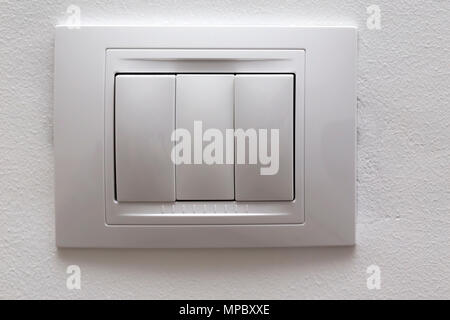 Two white lighting switchs on concrete wall separated by on false cap - close up view Stock Photo