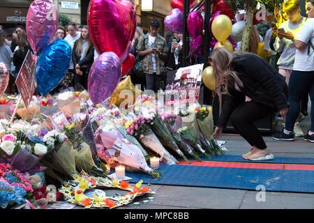 Manchester, UK. 22nd May, 2018. A young girls leaves a bunch of flowers at the memorial in St. Ann's Square in the center of Manchester, to remember the 22 victims of the bombing of the Manchester Arena, following the concert given by the American singer Ariana Grande. Credit: Rob Carter/Alamy Live News Stock Photo
