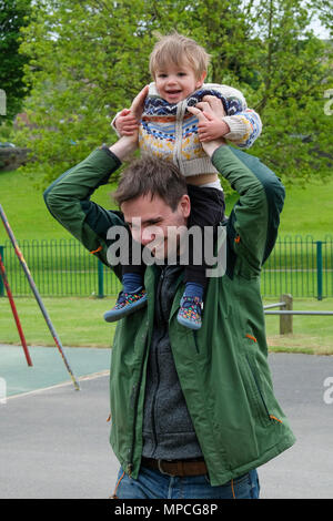 Young boy 18 months old being carried outdoors on father's shoulders Stock Photo