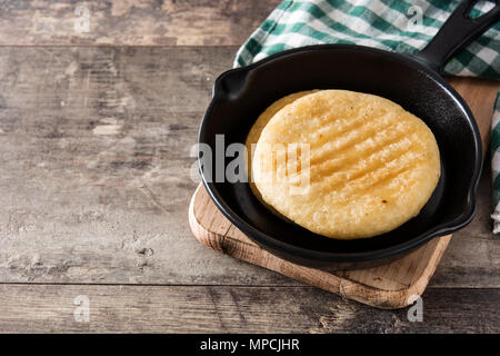 Arepas in frying pan on wooden table. Venezuelan typical food. Copyspace Stock Photo