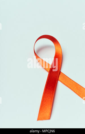 an orange ribbon, for multiple sclerosis awareness, on an off-white background with some blank space around it Stock Photo