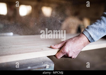 An unrecognizable man worker in the carpentry workshop, working with wood. Stock Photo