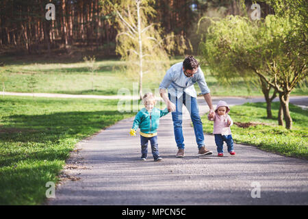 A father with his toddler children outside on a spring walk. Stock Photo