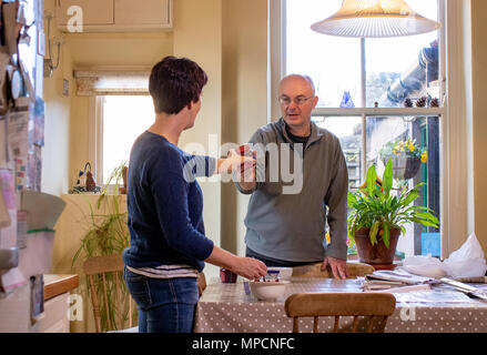 Mature couple are making a cranberry sauce together at home ready for thanksgiving dinner. Stock Photo