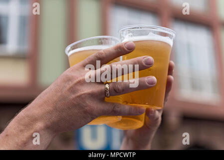 two hands and three full plastic cups with beer Stock Photo