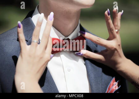 bride helps the groom to pull the bow-tie Stock Photo