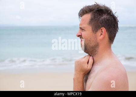 Worried caucasian man sucking his thumb standing on the tropical beach Stock Photo