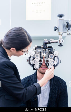 Optician and man at eye examination with phoropter