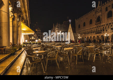 VENICE, ITALY - JANUARY 02 2018: night view of chairs and tables of a bar in Piazza San Marco with the Christmas tree in the background Stock Photo